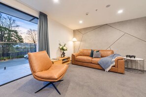 Uma sala de estar moderna com um sofá de couro, uma poltrona de couro e uma mesa lateral com abajur.