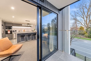 Une cuisine moderne avec un coin bar, une porte-fenêtre coulissante donnant sur un balcon et un fauteuil en cuir.