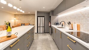 Una cocina moderna con una isla central, electrodomésticos de acero inoxidable y un amplio espejo como protector.