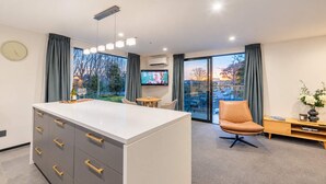 Habitación de hotel moderna con una isla grande, televisor de pantalla plana, un sillón de cuero cómodo y vistas a la ciudad.