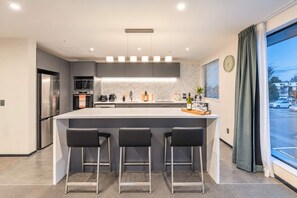 Une cuisine moderne dotée d’un îlot central, de tabourets de bar, d’un four à micro-ondes et d’un réfrigérateur.