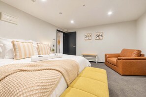Ein Hotelzimmer mit Bett, Sofa, Bank und Tür.
