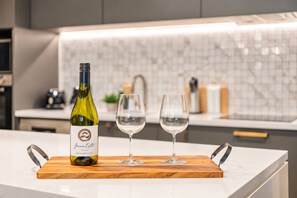 Une bouteille de vin et deux verres sur une planche en bois, dans une cuisine moderne.