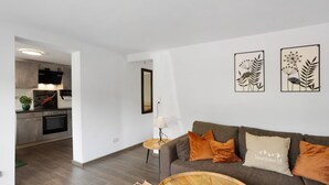 A modern living room with a grey sofa, a wooden coffee table, and a kitchen in the background. - Apartment 'Selbecke' with Pool and Garden (Kirchhundem)