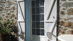 A stone wall, a white door with glass panels, a white chair, and a potted plant.