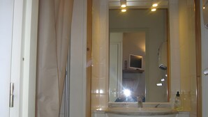 A bathroom with a large mirror, a sink, and a shower.
