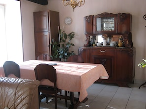 Un coin repas avec une table dressée pour deux personnes, un meuble en bois orné d’un miroir et une plante en pot.
