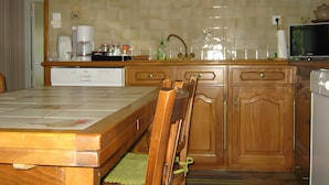 A kitchen with wooden cabinets, a dishwasher, a coffee maker, and a television.