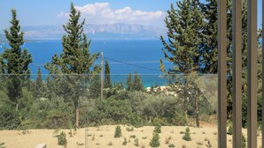 A coastal view with a clear sky, a sandy landscape, and dense greenery.