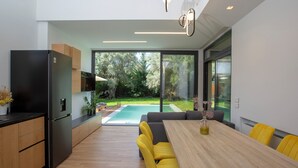 A modern kitchen with a built-in refrigerator, wooden cabinets, and a large dining table with yellow chairs.