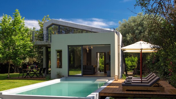 A modern house with a swimming pool, outdoor furniture, and a garden.