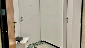 Ein Hotelzimmer mit einer weißen Tür, einem kleinen Schreibtisch mit einem schwarzen Gegenstand darauf und einer grünen Matte mit Zeichentrickfiguren auf dem Boden.