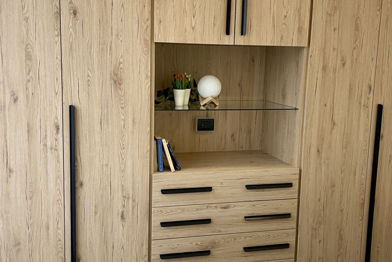 A wooden cabinet with a glass shelf, a small plant, and a decorative sphere.