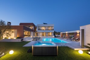 Une maison moderne dotée d’une piscine, d’un jacuzzi et d’un espace salon extérieur.