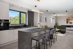 Una cocina moderna con una isla grande, taburetes de bar y vistas al exterior.