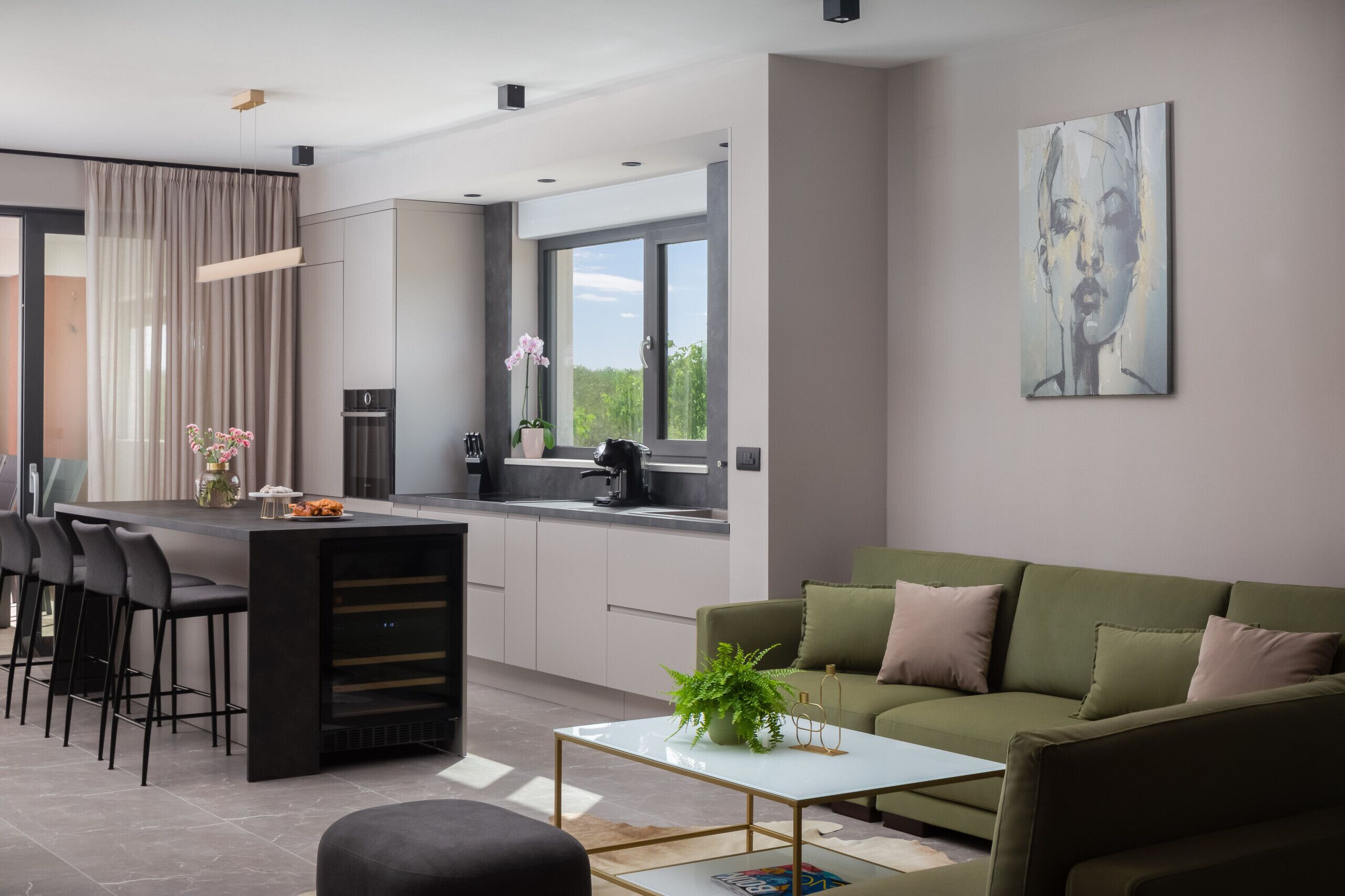 Eine moderne Küche mit Essbereich, einem grünen Sofa und einem Gem älde an der Wand.
