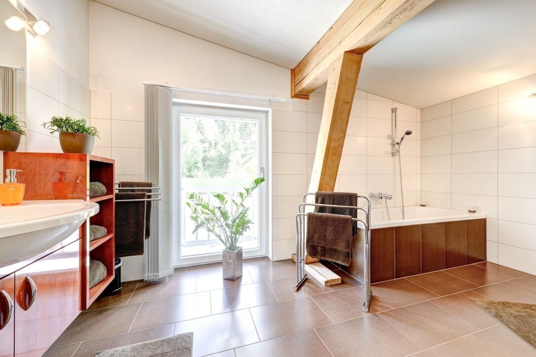 Een moderne badkamer met een badkuip, douche en een groot raam.