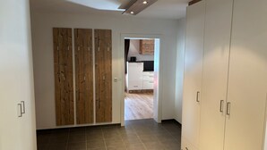 A spacious room with a tiled floor, a wooden panel wall, and a wardrobe. - Bocks Apartments 61 (Dalaas)