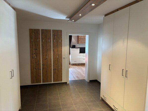 Una habitación amplia con suelo de baldosas, un panel de madera y un armario.