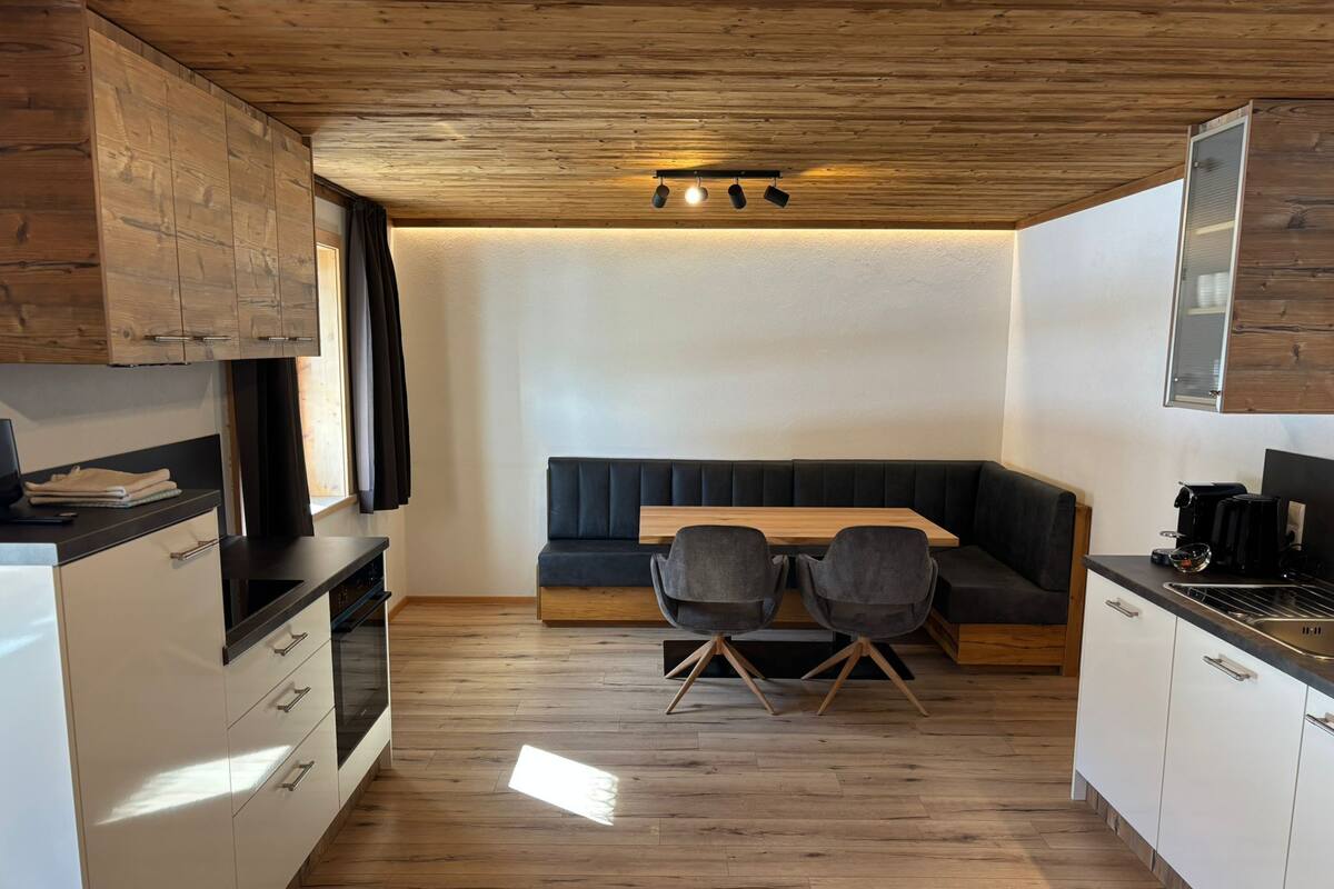 A modern kitchen with wooden cabinets, a dining table with chairs, and a built-in bench.
