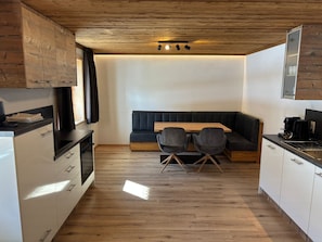A modern kitchen with wooden cabinets, a dining table with chairs, and a built-in bench.