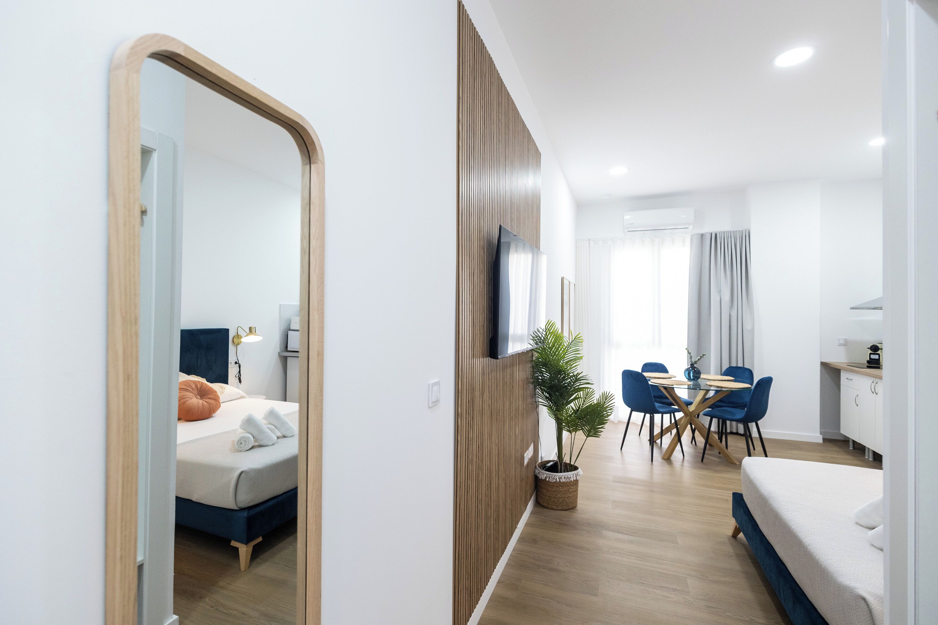 Una habitación de hotel moderna con una cama, un escritorio, un comedor y un espejo grande.