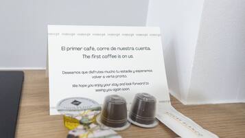 Una mesa de madera con una taza de café, un paquete de café y una tarjeta con texto en español.