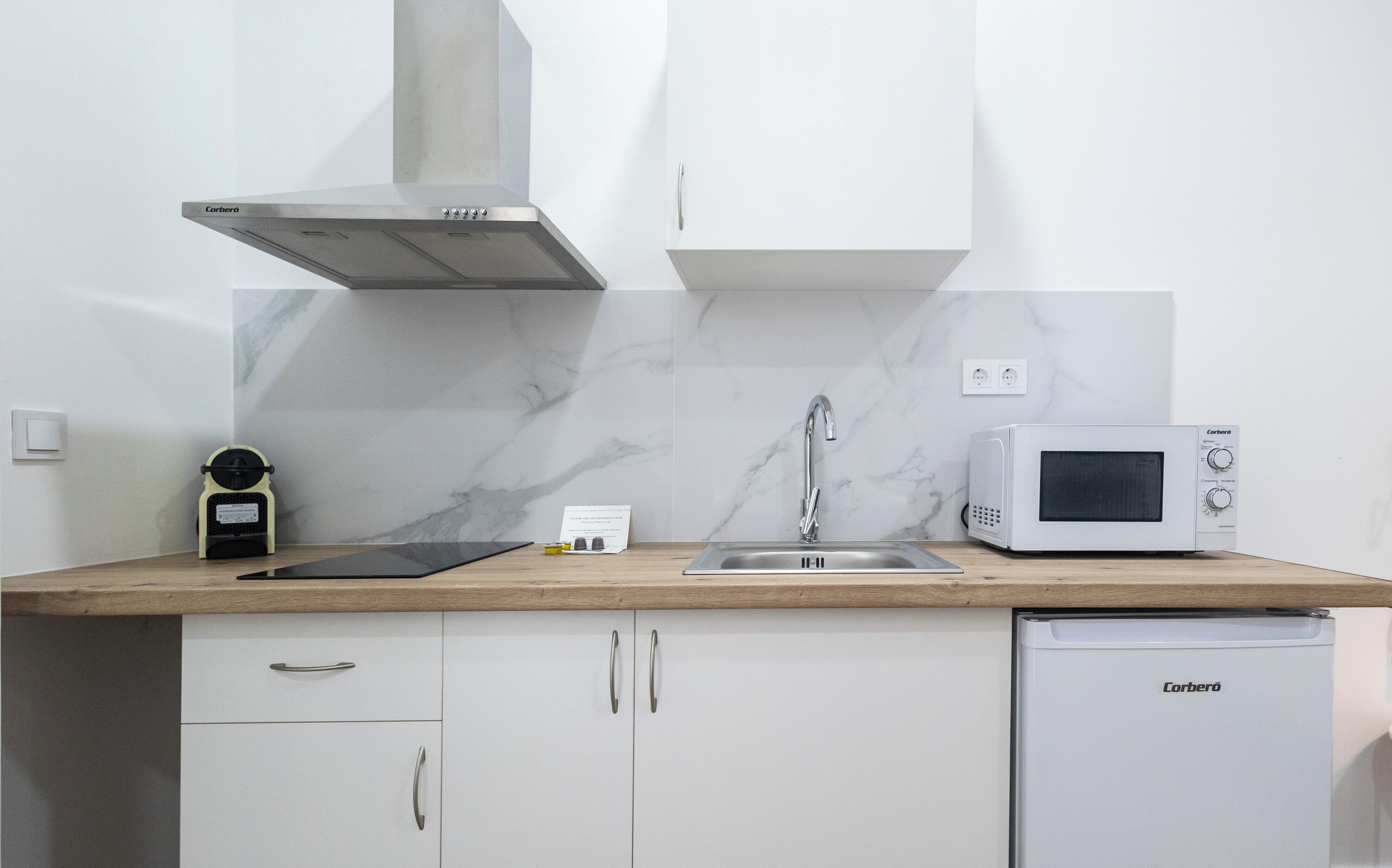Una cocina compacta con microondas, lavavajillas y pileta.