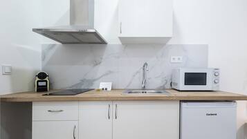 Una cocina compacta con microondas, lavavajillas y pileta.