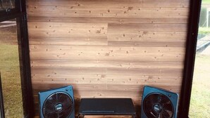 Una habitación con paneles de madera y dos ventiladores negros sobre un banco.
