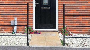 A brick building with a black door, a small porch, and a number plaque. - Modern 4BR House in the Centre Spacious & Ideal for Families and Contractors (Overdale)