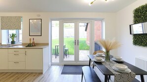 A modern kitchen with a dining area, featuring a large window, a dining table set with plates, and a bench. - Modern 4BR House in the Centre Spacious & Ideal for Families and Contractors (Overdale)