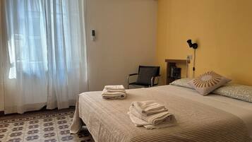 Habitación de hotel con una cama, una silla, un escritorio y un equipo de aire acondicionado.