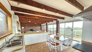 A modern kitchen with white cabinets, a wooden countertop, and a dining area with white chairs.