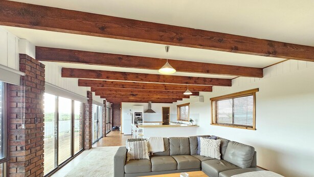 A spacious living area with a large sectional sofa, a wooden coffee table, and a view of the backyard through large sliding glass doors.
