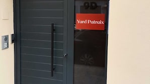 Uma porta escura com puxador e painel de vidro.