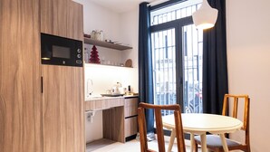 Uma cozinha moderna com armários de madeira, micro-ondas embutido e área de refeições com mesa redonda e cadeiras de madeira.