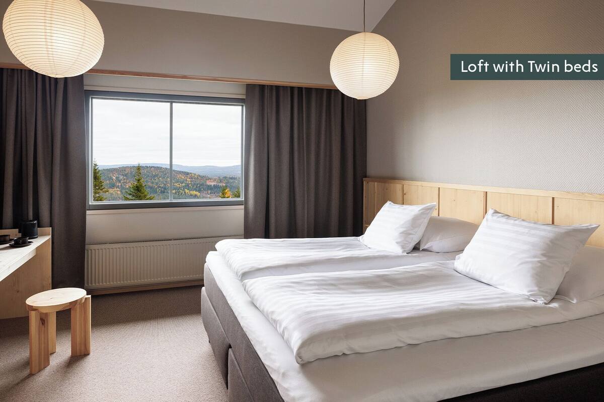 Un appartement-loft avec deux lits simples, un bureau et une vue sur l’extérieur.