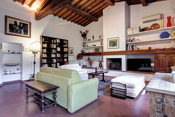 A living room with a sofa, a coffee table, a fireplace, a bookshelf, and a television.