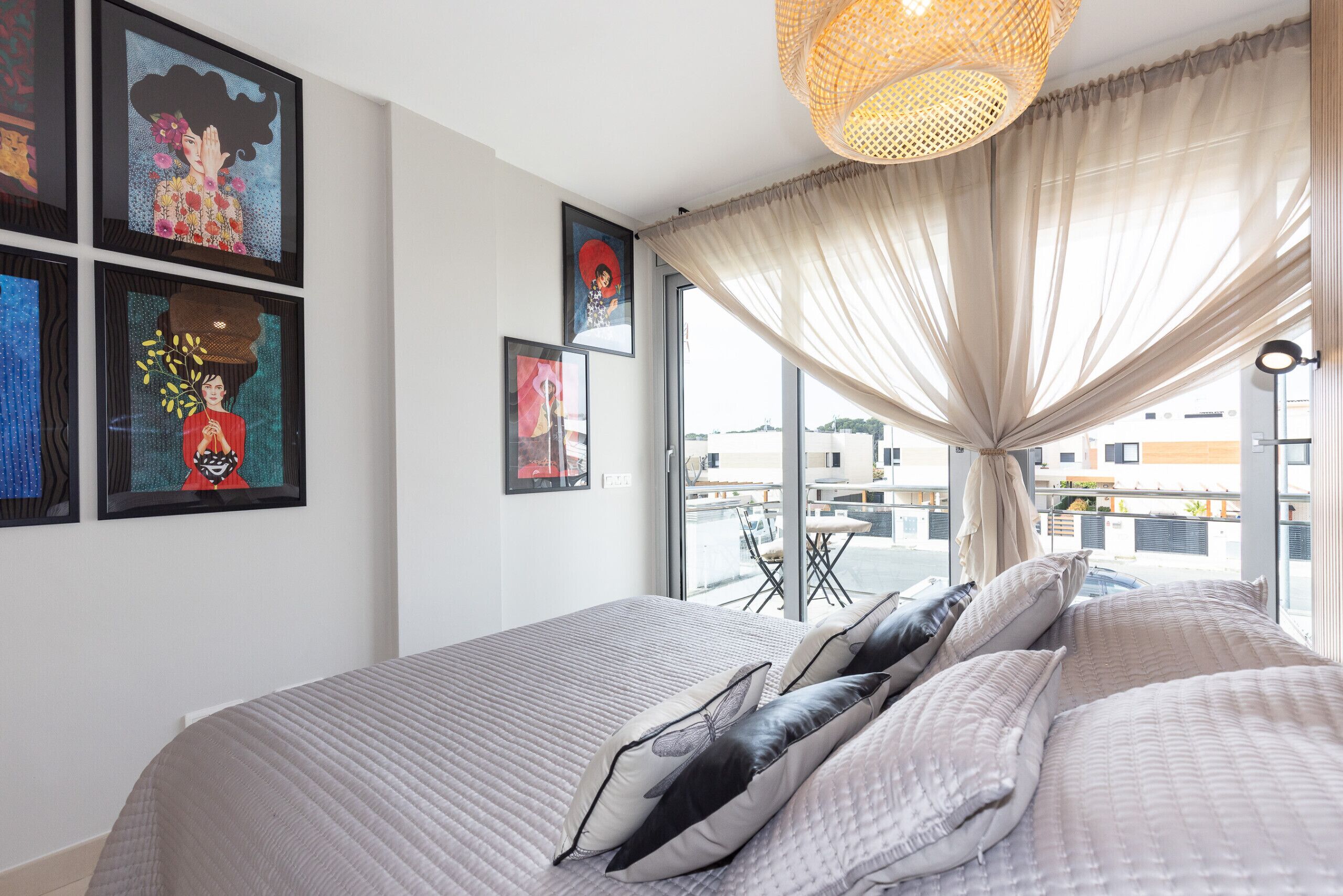 A bedroom with a large bed, a view of the outside, and artwork on the wall.