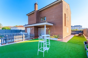 A brick house with a patio, a white fence, and a small garden.
