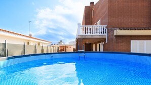A swimming pool with a tiled edge, surrounded by buildings with brick facades and a balcony.