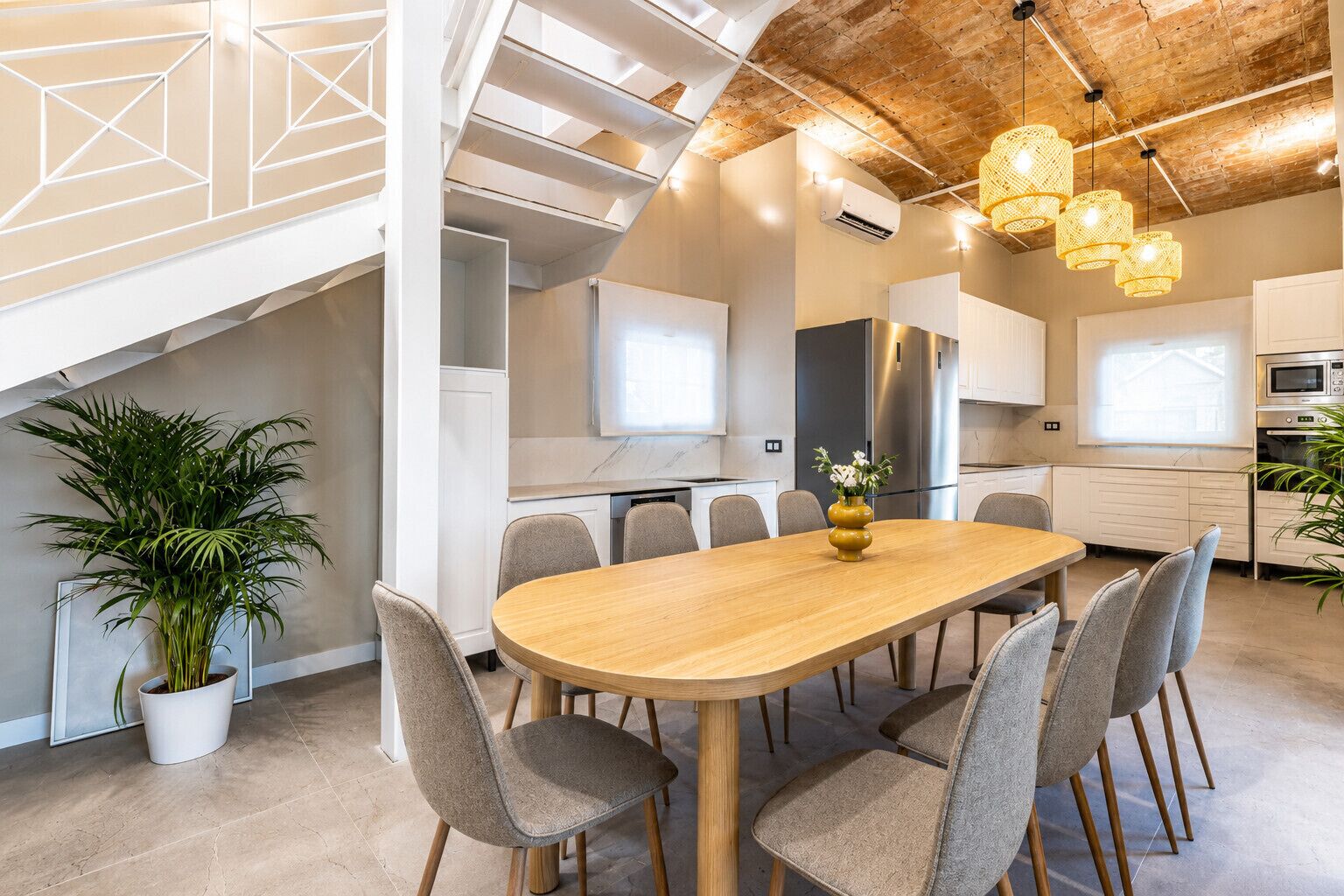 Een moderne keuken met een centraal eiland, witte kasten en een eethoek met een houten tafel en stoelen.