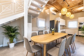 Uma cozinha moderna com uma ilha central, armários brancos e um espaço de refeições com mesa e cadeiras de madeira.