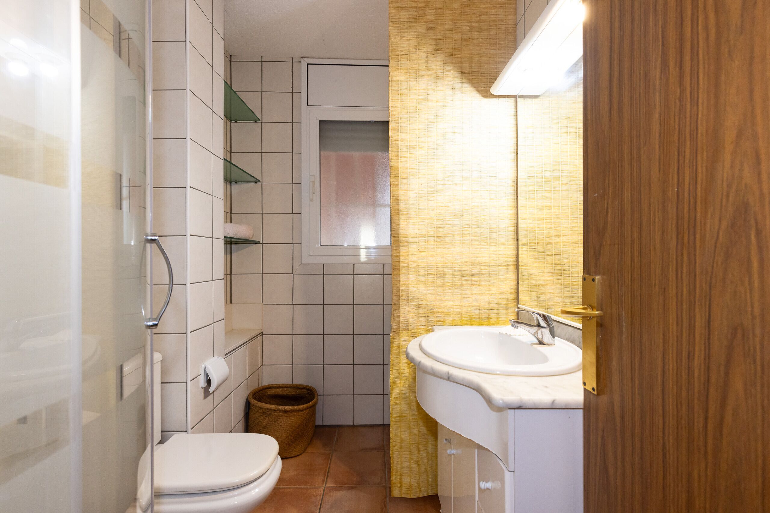 A compact bathroom with a toilet, sink, and shower area.