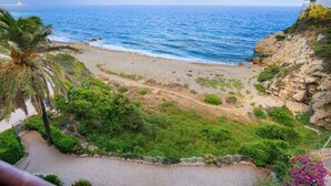 A coastal view with a beach, rocky cliffs, and greenery. - NAUTICO Apartment (Salou)