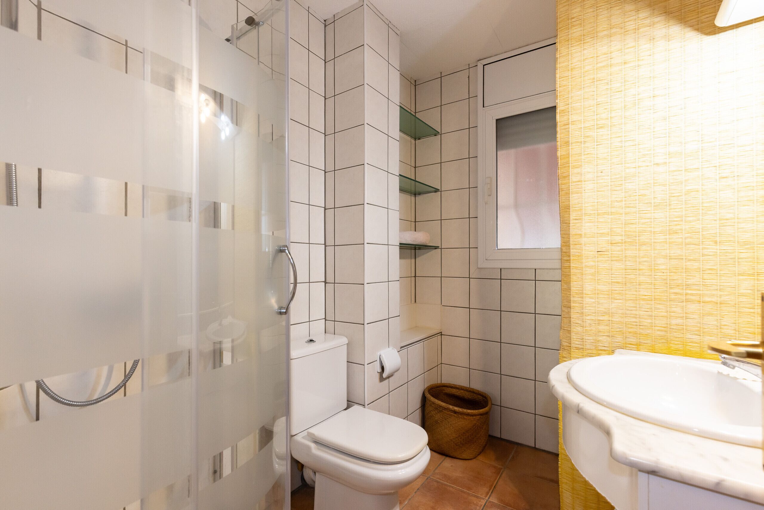 Une salle de bain comprenant des toilettes, une douche, un lavabo et une fenêtre.