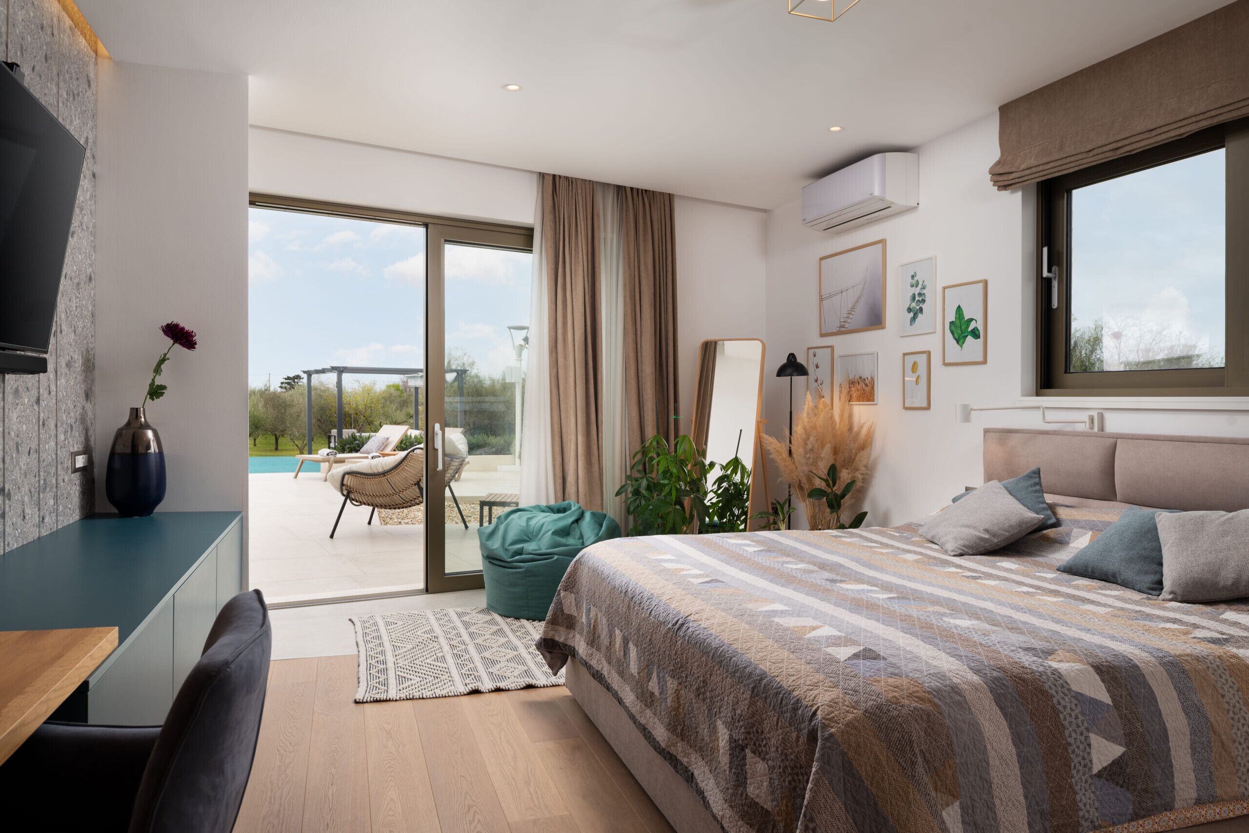Ein modernes Schlafzimmer mit einem großen Bett, einem Schreibtisch und Blick ins Freie.