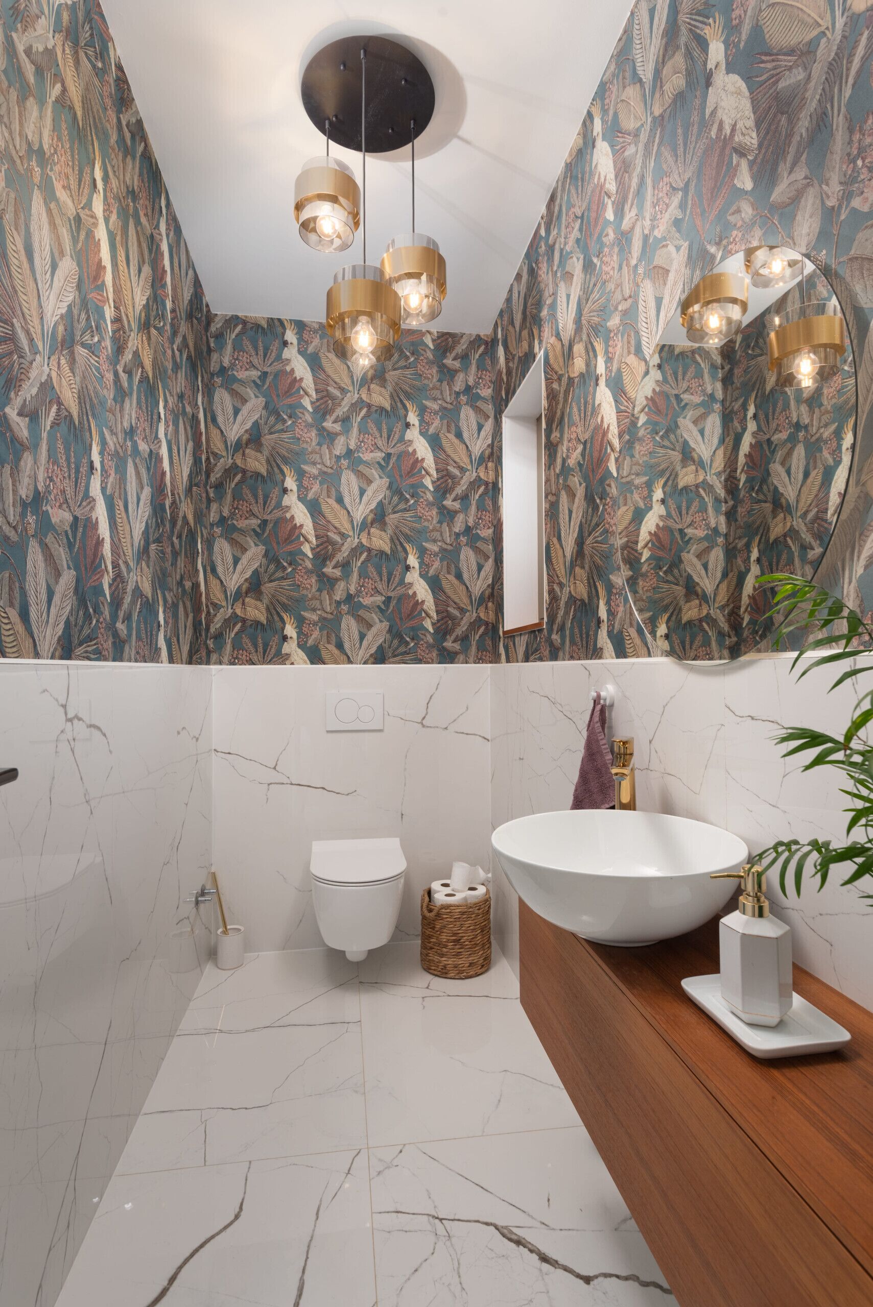 A modern bathroom with a white marble floor, a wooden vanity, a white sink, and a toilet.