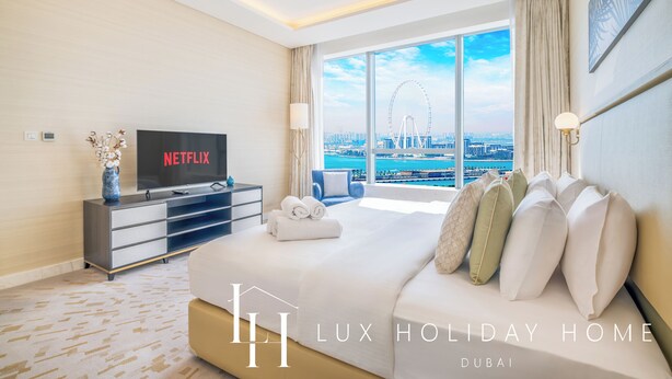Een moderne hotelkamer met een groot bed, een flatscreen televisie en uitzicht op een stadsgezicht en een reuzenrad.